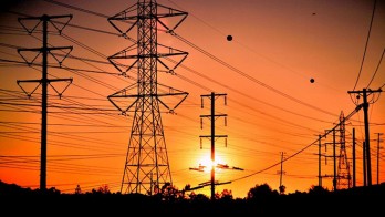 Transmission towers and power lines in front of a beautiful sunset.