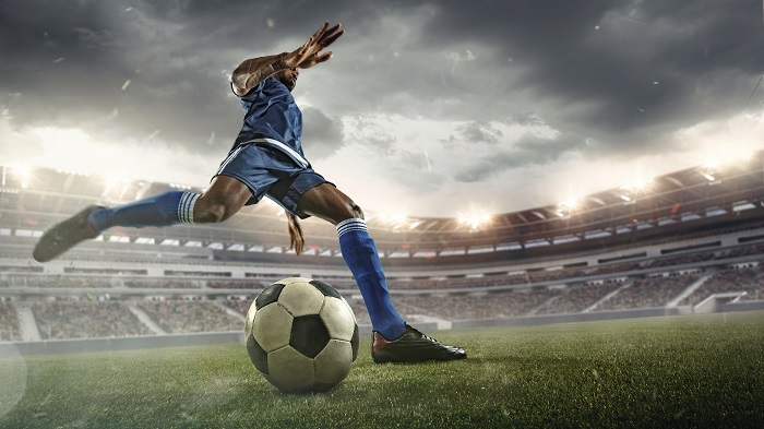 Soccer player kicking ball in stadium.