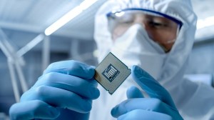 Worker in semiconductor wafer fab holding a semiconductor chip.